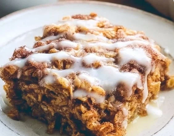 Delicious cinnamon roll baked oatmeal in a rustic dish topped with icing.
