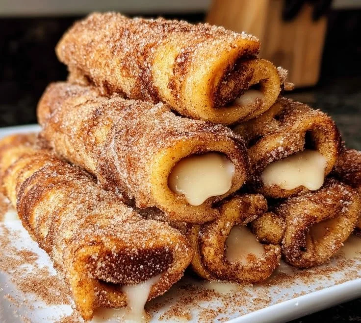 Cinnamon French Toast Roll Ups served on a plate with syrup and berries.