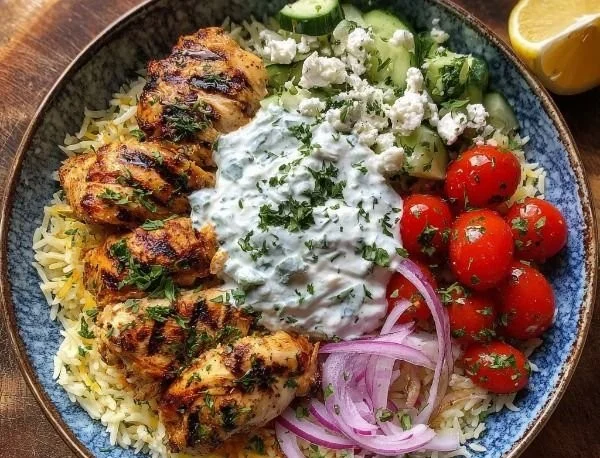 Greek chicken rice bowl with creamy tzatziki sauce garnished with herbs