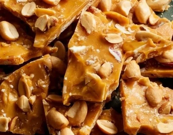 Bowl of homemade peanut brittle on a wooden table