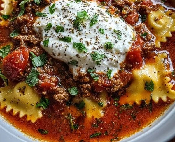 Bowl of lasagna soup topped with ricotta cheese and fresh herbs