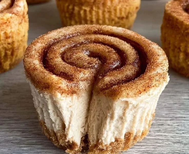 Mini cinnamon roll cheesecakes topped with cinnamon swirl and cream cheese frosting