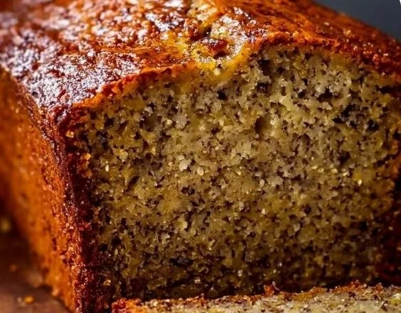 Loaf of perfect moist banana bread with sliced pieces on a wooden table