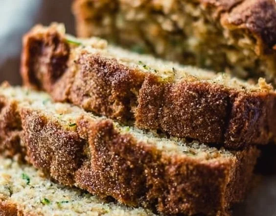 Loaf of perfectly baked zucchini bread on a wooden cutting board