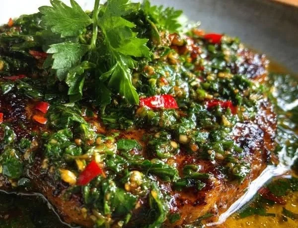 Zesty Argentinian chimichurri sauce served in a bowl with fresh herbs.