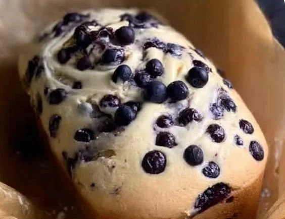 Sliced blueberry cream cheese loaf with fresh blueberries on a plate