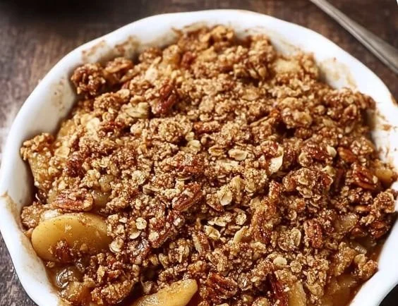 Healthy apple crisp topped with oatmeal and pecans, served in a bowl
