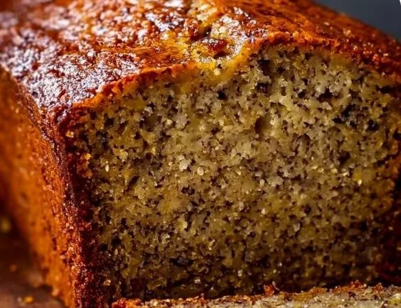 A fresh loaf of perfect moist banana bread on a wooden cutting board.