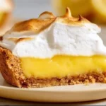 A slice of Vegan Lemon Meringue Pie with a fluffy meringue topping and lemon filling