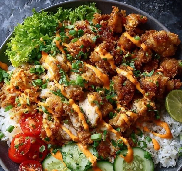 Crispy Bang Bang Chicken Bowl topped with green onions and sauce