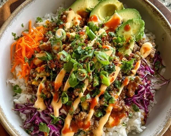 Ground turkey rice bowl topped with spicy bang bang sauce and vegetables
