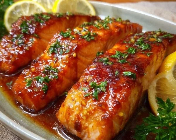 Maple-glazed baked salmon served on a plate with vegetables.