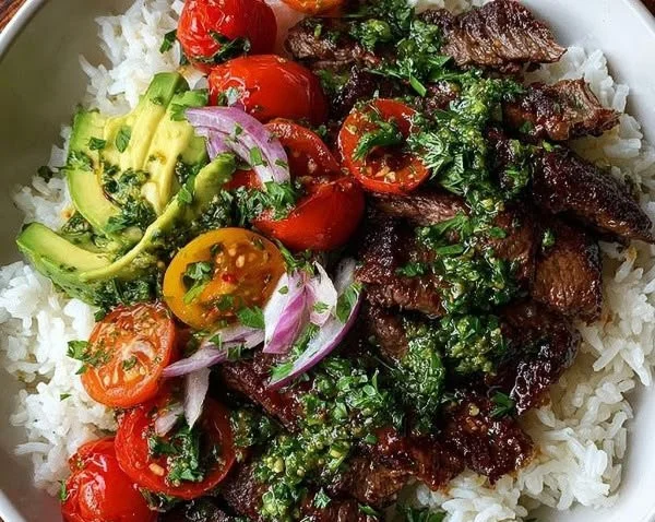 Skirt steak rice bowls with chimichurri sauce garnished with fresh herbs.