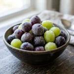 A bowl of frozen grapes, perfect for a refreshing summer snack.